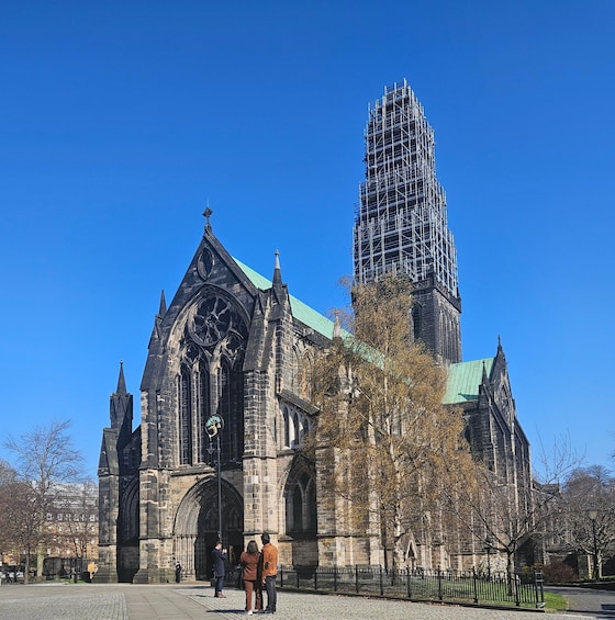 A historic church with Gothic architecture, a tall tower under construction, and a clear blue sky. 3
