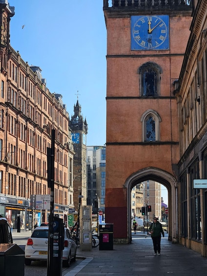 A street with a clock tower, a pedestrian, and cars. 4