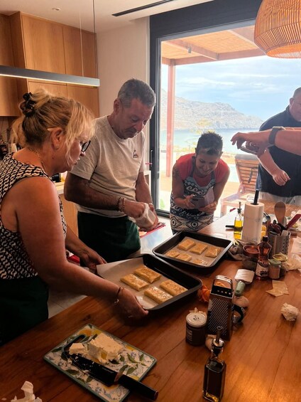 A group of people preparing food in a kitchen with a view of the sea. 3