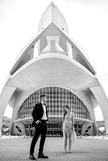 A couple standing in front of a modern architectural building with a pointed roof and large windows. 5