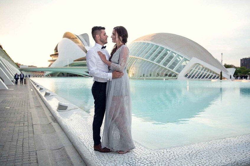 A couple standing by a pool with a modern architectural structure in the background. 4