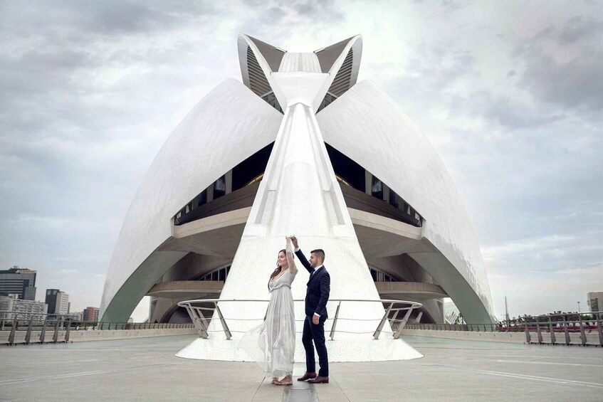 A couple dancing in front of a modern architectural structure with a unique design. 1