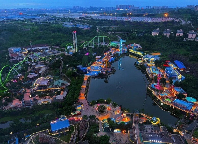 An amusement park at dusk with roller coasters, a lake, and illuminated buildings. 4