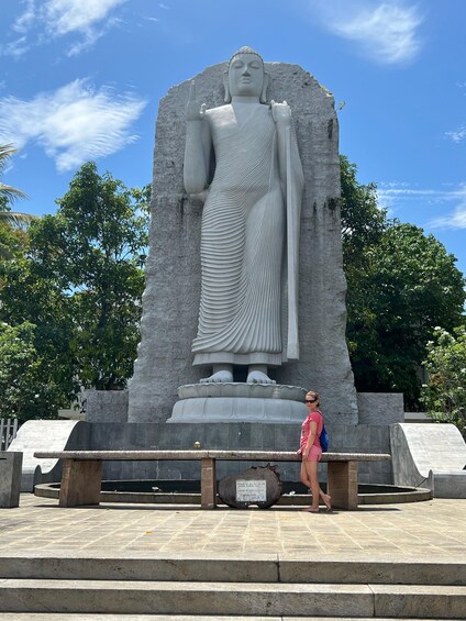 A large stone Buddha statue with a bench in front. 3