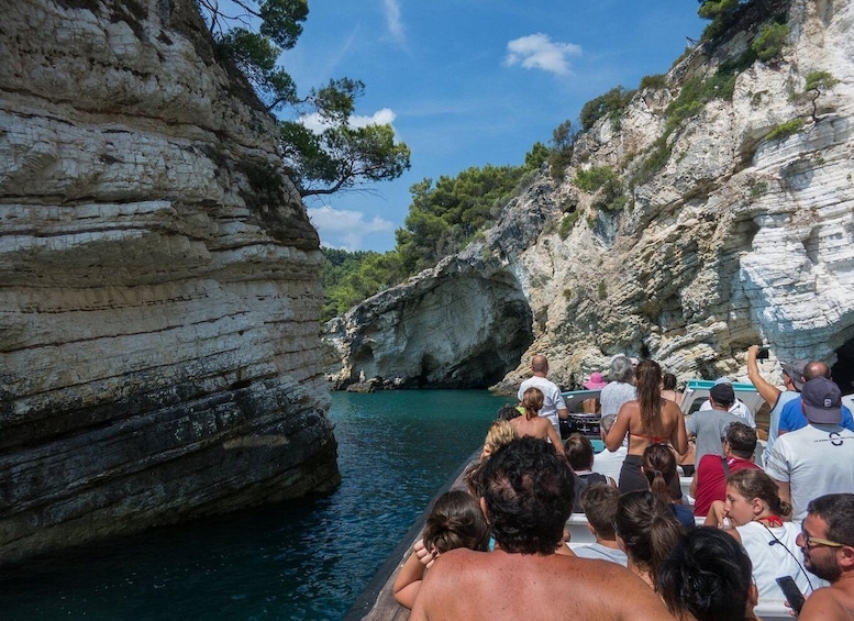 A group of people on a boat near rocky cliffs and clear blue water. 1