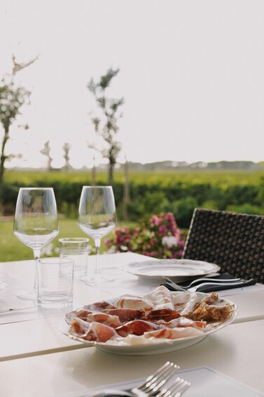 A table with a plate of food, two wine glasses, and a fork. 1