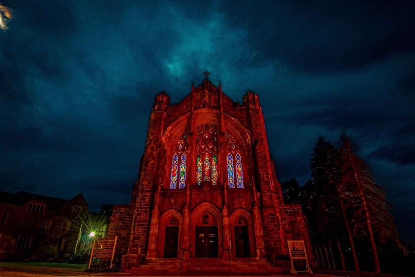 A Gothic-style church with stained glass windows and a cross on top, under a dark, cloudy sky. 1