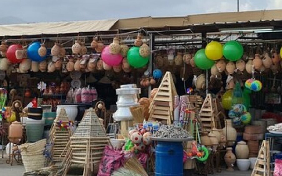 A market stall with various items including colorful balloons, wooden toys, and pottery. 3