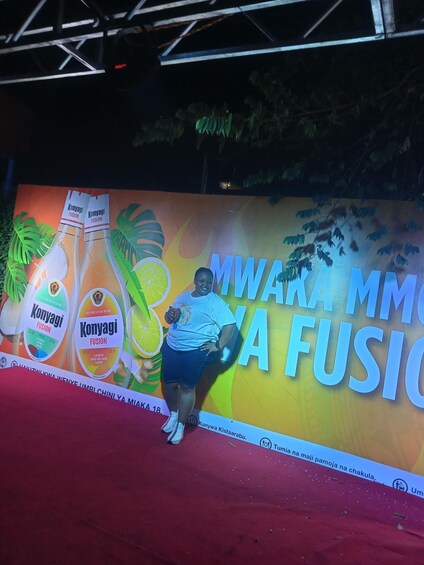Une scène sur laquelle est affichée une grande publicité pour Konyagi Fusion, avec une personne debout devant. 2