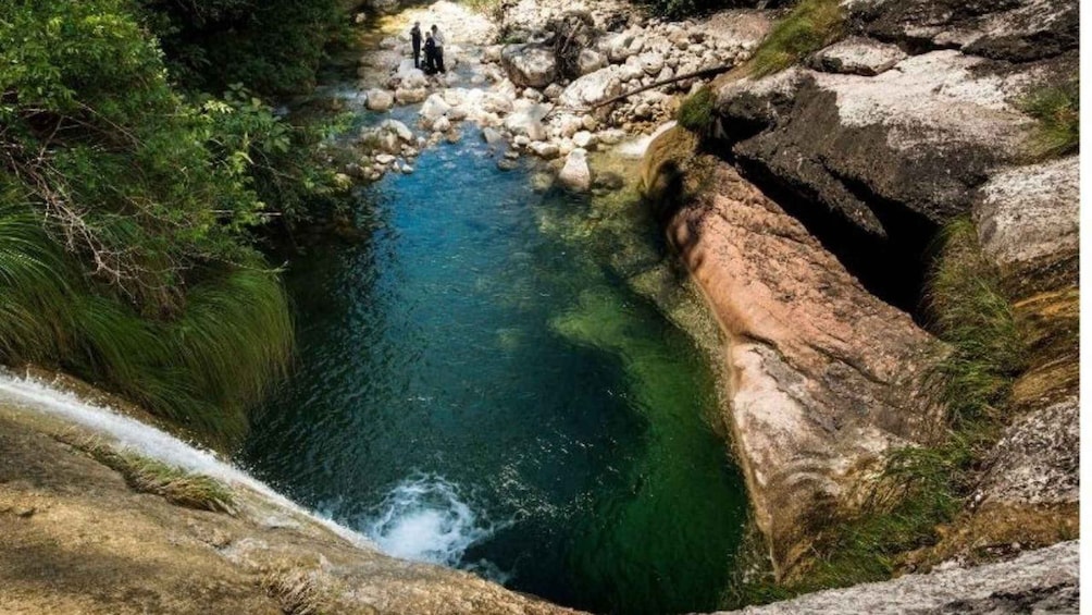 A clear river flowing through a rocky gorge with lush greenery on the sides. 2