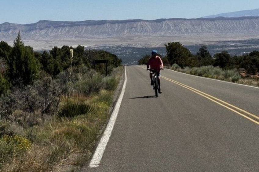A cyclist on a two-lane road with a mountainous backdrop. 4