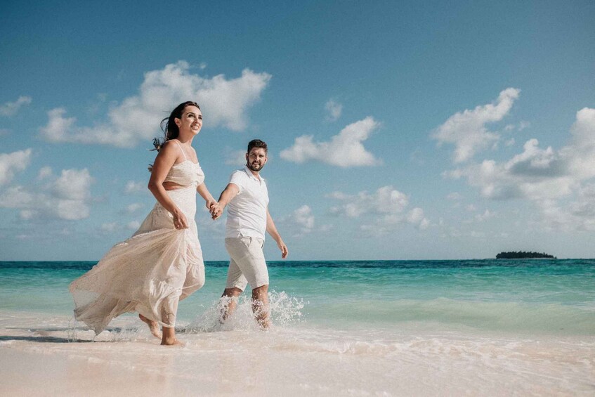 A couple running on a beach with clear skies and turquoise water. 2