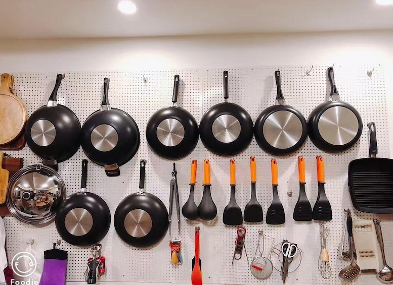 A kitchen wall with various cooking utensils and cookware. 5