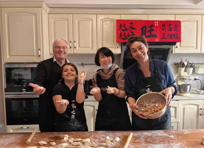 A group of people in a kitchen preparing food, with a red sign and kitchen appliances in the background. 3