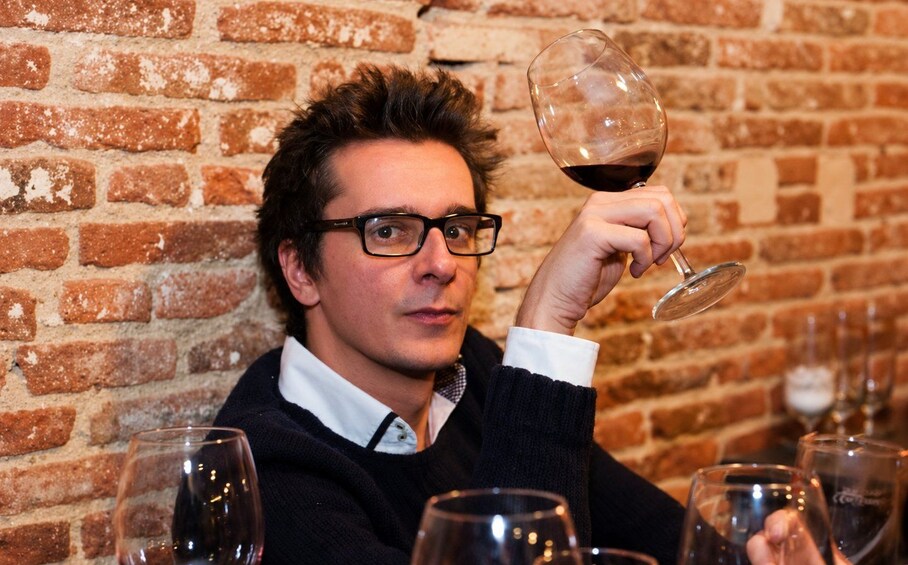A person holding a wine glass with a brick wall in the background. 5