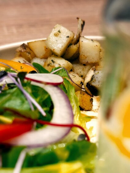 A close-up of a salad with roasted potatoes, greens, and radishes. 3