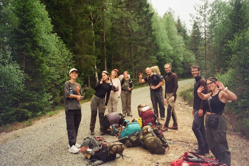 A group of hikers with backpacks and gear on a forest trail. 1