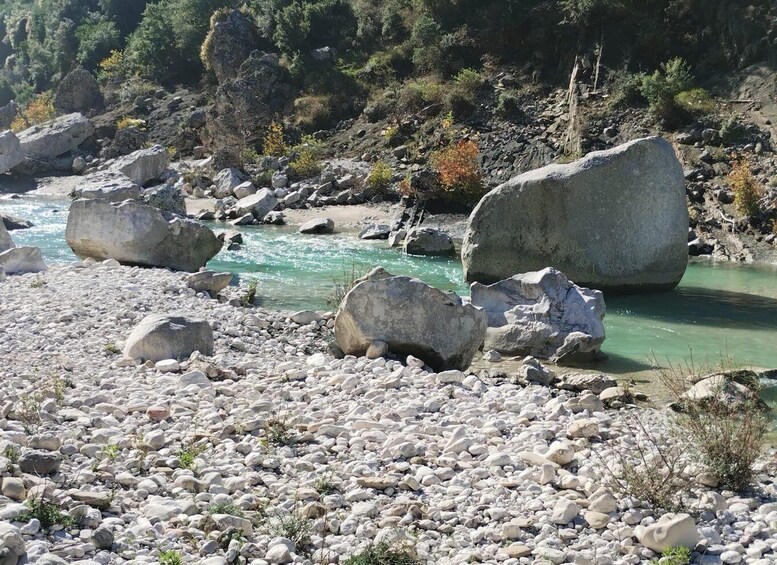 A river with clear water, surrounded by large rocks and sparse vegetation. 2