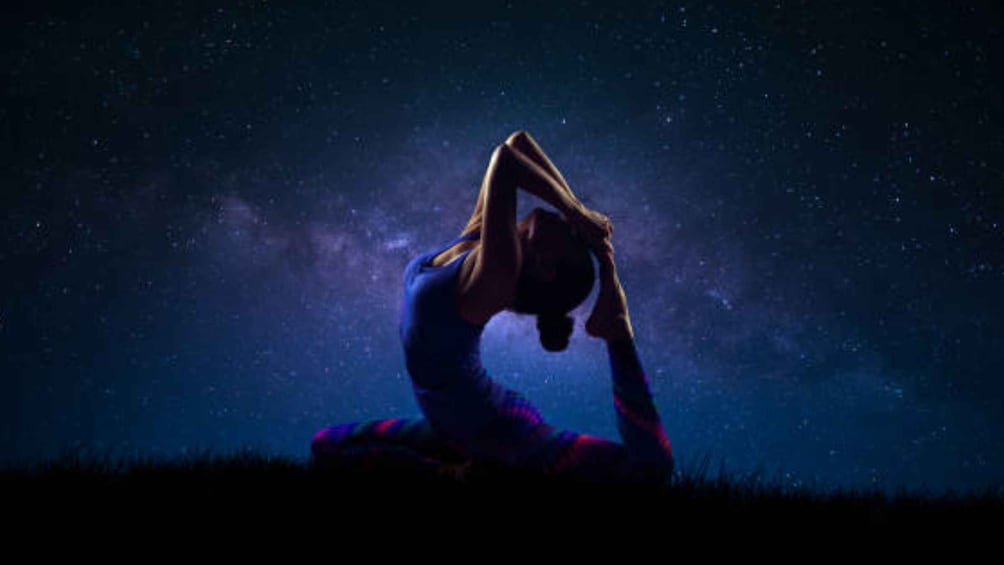 A person in a yoga pose against a starry night sky. 1