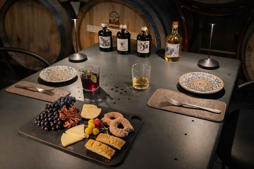 Een gedekte tafel met borden, bestek, een fles wijn en een assortiment kazen en fruit. 3