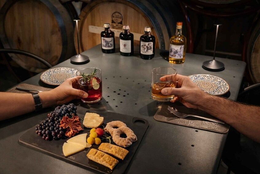 Twee personen die met drankjes proosten, een fles whisky en een bord met kaas en fruit. 1