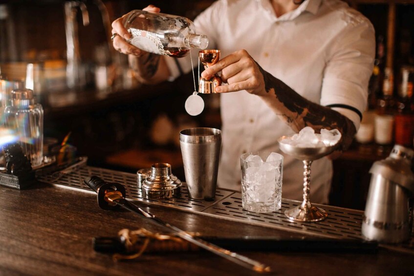 Een barman giet een drankje in een glas met ijs. 2