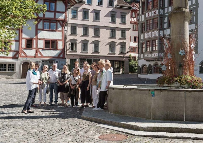 A group of people standing in a cobblestone square with historic buildings in the background. 2