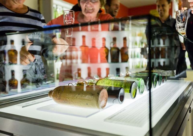 A display of various bottles and a large corked bottle in a glass case. 1