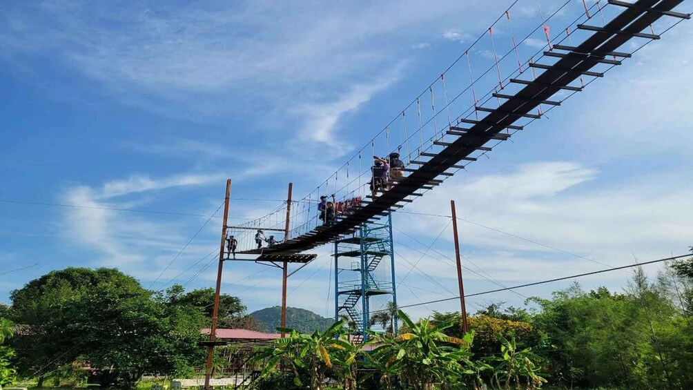A zip line with people riding it, surrounded by lush greenery and a clear sky. 1