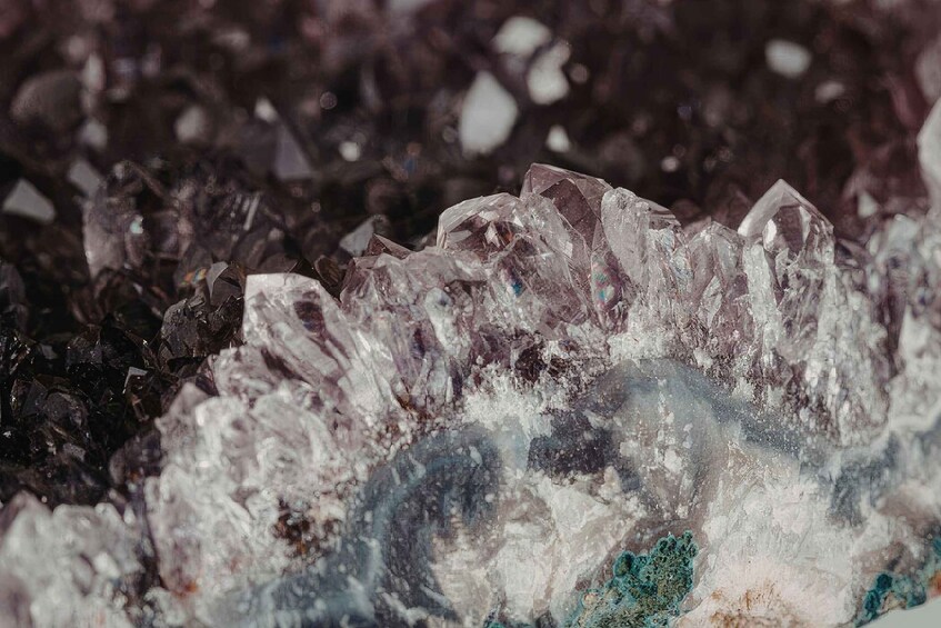 A cluster of clear, faceted crystals with a rough, dark background. 4
