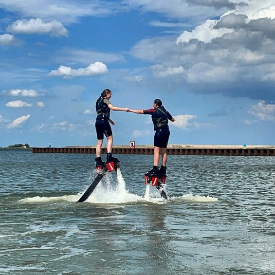 Two people water skiing on a calm body of water with a pier in the background. 2