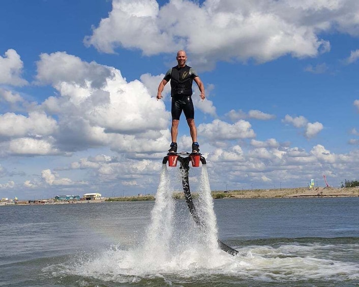 A person water skiing on a body of water with a clear sky and clouds in the background. 1