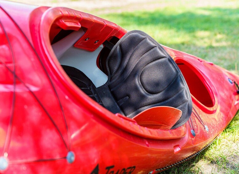 A red kayak with a black glove resting inside. 3