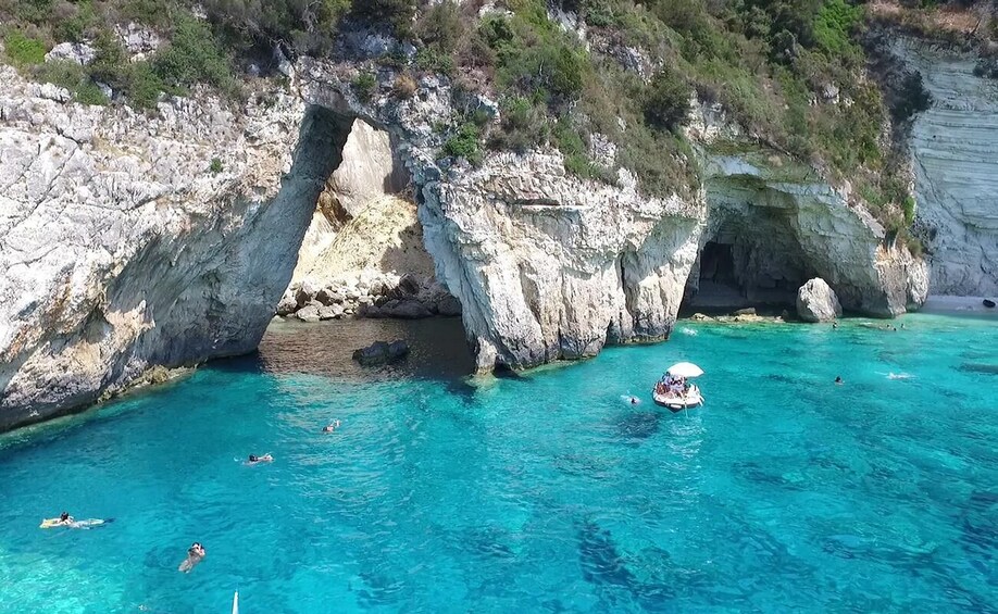 A coastal area with clear turquoise water, rocky cliffs, and a small boat with an umbrella. 2