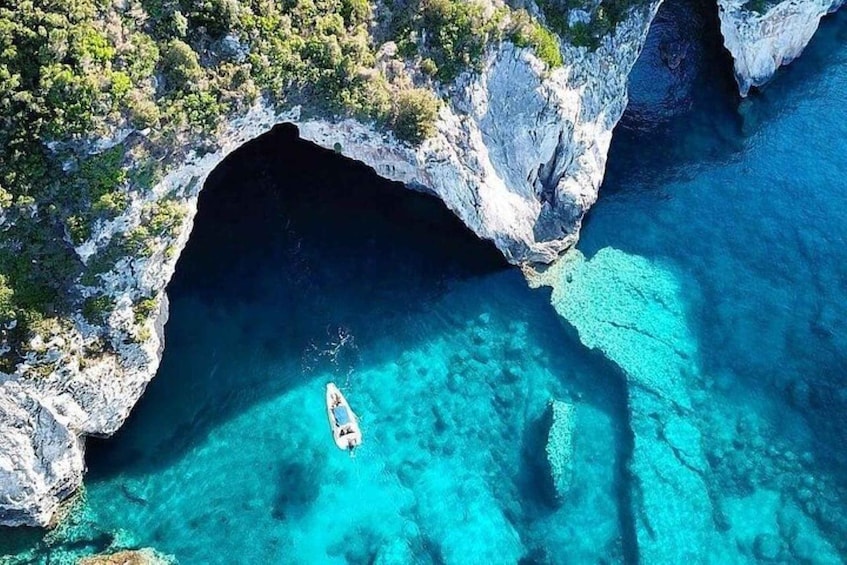 A boat in a clear blue cove surrounded by rocky cliffs. 3