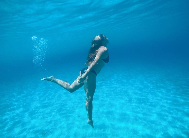 A person swimming underwater in clear blue water. 5