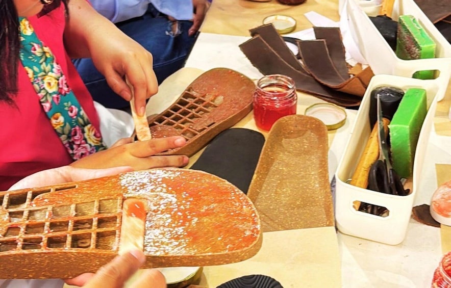 A waffle iron with a waffle being pressed, a jar of red syrup, and various tools and utensils on a table. 1