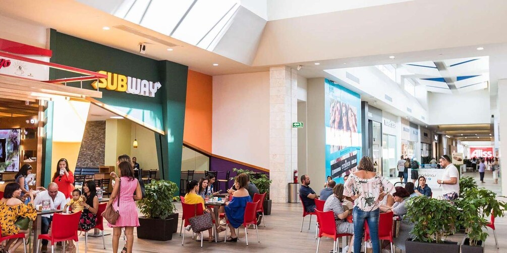 A SUBWAY restaurant inside a shopping mall with people dining and walking around. 1
