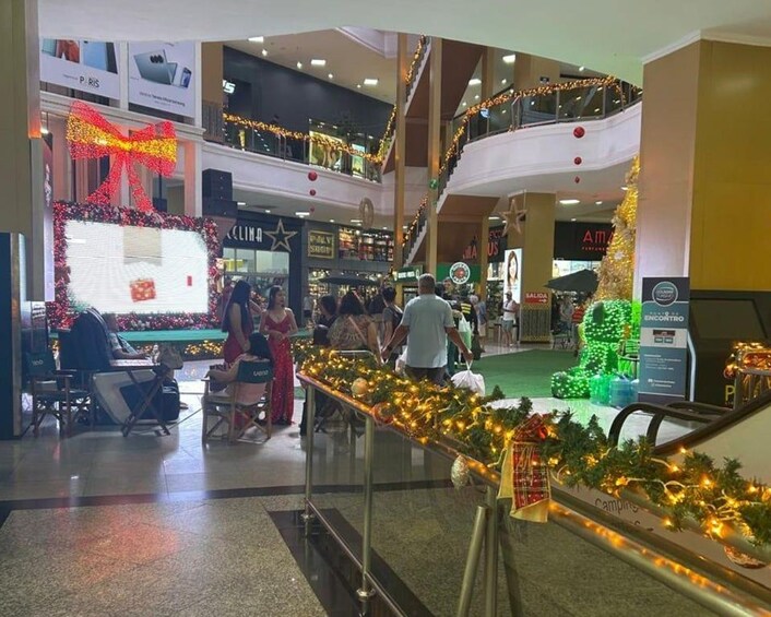 Un centre commercial décoré pour Noël, avec un grand nœud, un sapin de Noël et des guirlandes lumineuses festives. 2