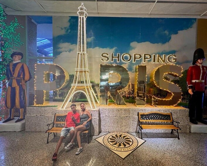 Une zone commerciale avec une grande tour Eiffel illuminée et, en arrière-plan, l  ’inscription « SHOPPING PARIS ». 3