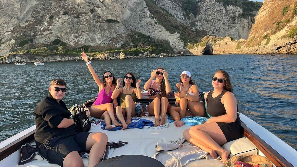 Een groep mensen op een boot, met rotsachtige kliffen op de achtergrond. 3