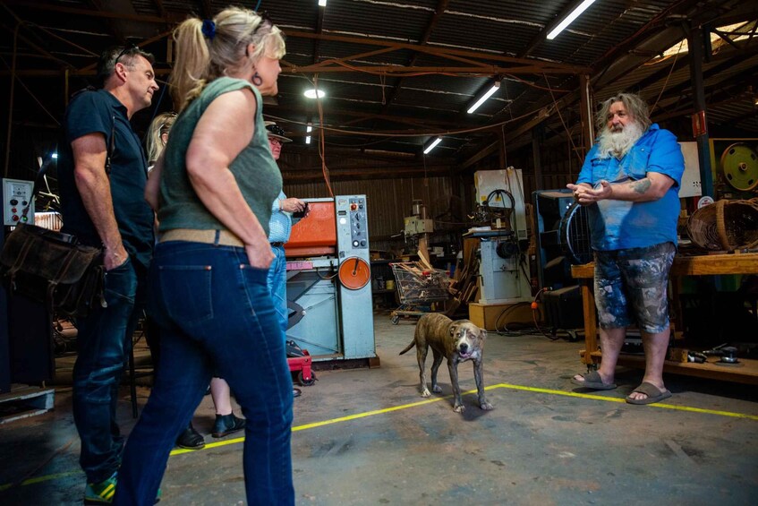 A workshop with people and a dog, featuring machinery and tools. 3