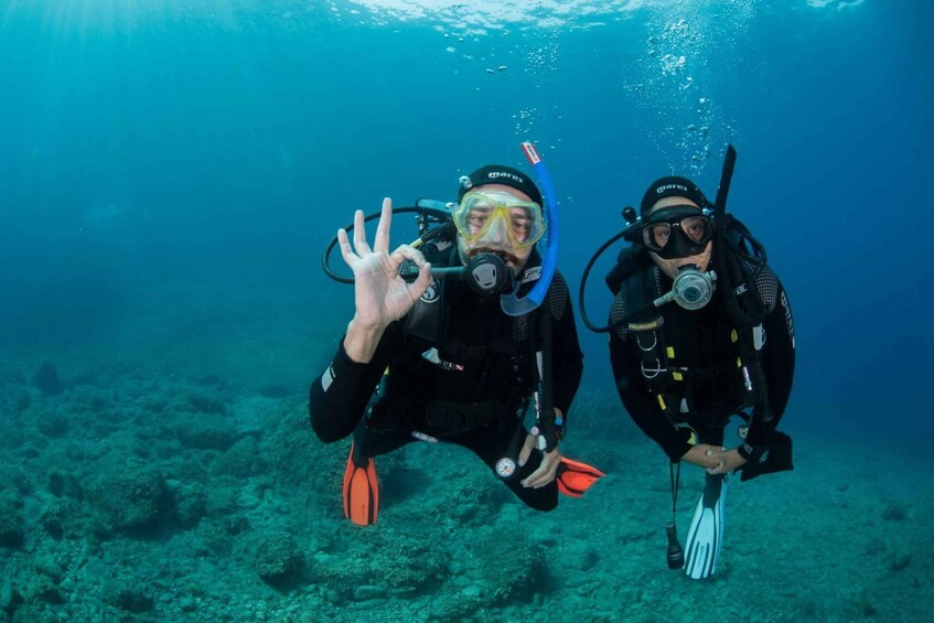 Two scuba divers underwater with fins and scuba gear. 5