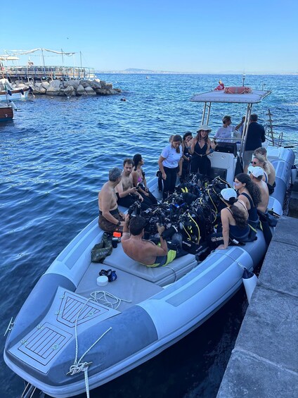 A group of people on a boat preparing for a dive, with scuba gear and a life jacket visible. 3