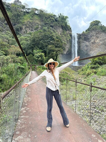 Una persona cruzando un puente colgante, con una cascada al fondo. 4