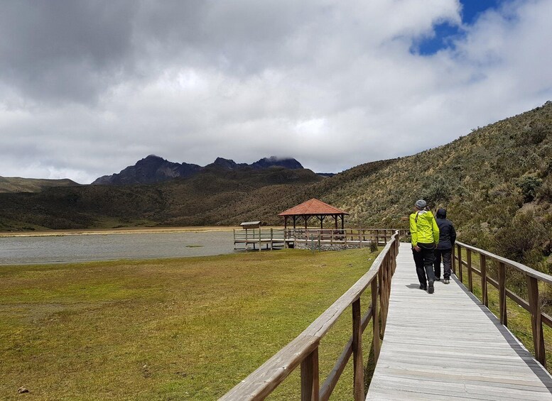 Un muelle de madera que lleva a un pabellón junto a un lago, con montañas al fondo. 3