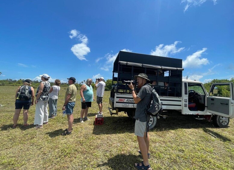 A group of people standing in a field with a white truck and a black canopy. 3