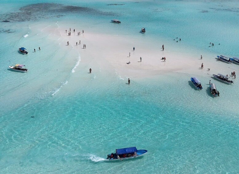 A tropical beach with clear turquoise waters, a sandy shore, and several boats. 1