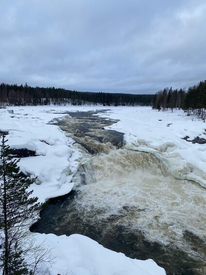 A river flowing through a snowy landscape with dense forests on either side. 1