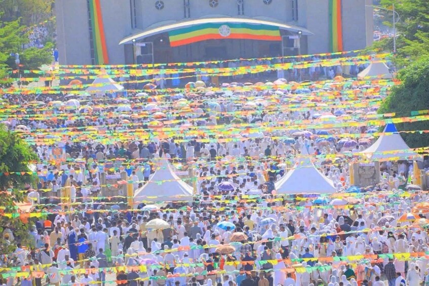A large gathering of people at a public event with tents and colorful decorations. 5